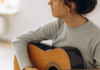 Young,Woman,Playing,Guitar,In,Bedroom,At,Home